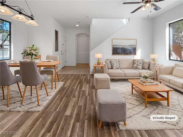 living room featuring arched walkways, wood finished floors, a wealth of natural light, and a ceiling fan