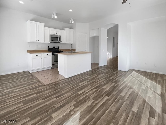 kitchen with appliances with stainless steel finishes, arched walkways, dark wood-type flooring, and open floor plan