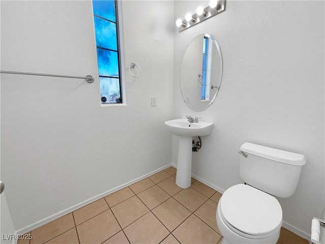 half bathroom with toilet, a baseboard heating unit, baseboards, and tile patterned floors