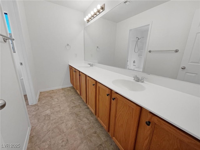 full bath featuring double vanity, baseboards, a shower, and a sink