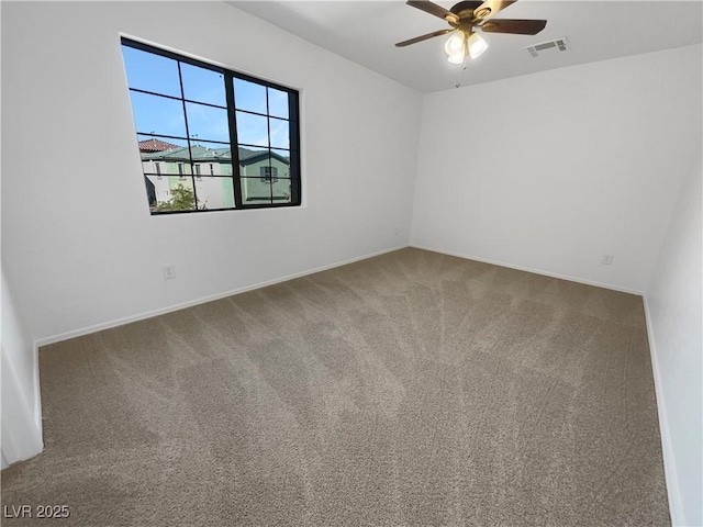 empty room with carpet floors, visible vents, ceiling fan, and baseboards