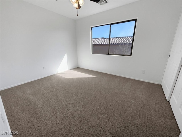 empty room with a ceiling fan, carpet flooring, visible vents, and baseboards