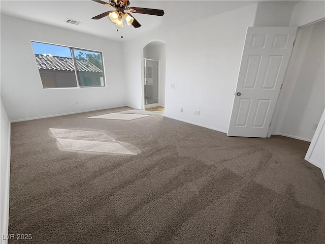 unfurnished bedroom featuring baseboards, visible vents, arched walkways, and carpet flooring