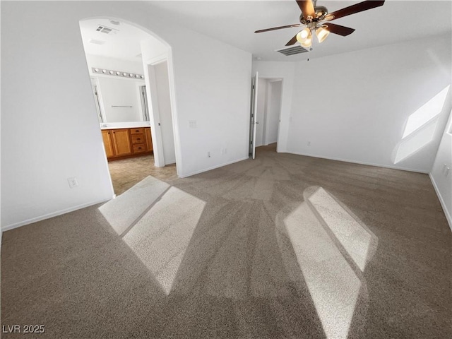 unfurnished bedroom featuring arched walkways, connected bathroom, visible vents, and light colored carpet