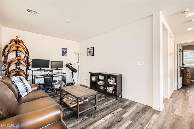 living room featuring baseboards, visible vents, and wood finished floors