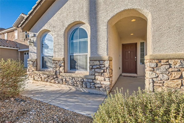 entrance to property featuring stone siding and stucco siding