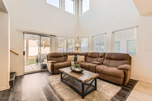 living area featuring a high ceiling, baseboards, and wood finished floors