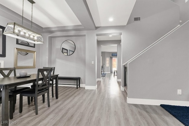 dining area featuring stairway, light wood-type flooring, visible vents, and baseboards