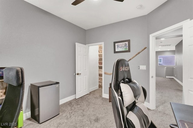 office space featuring light carpet, ceiling fan, visible vents, and baseboards