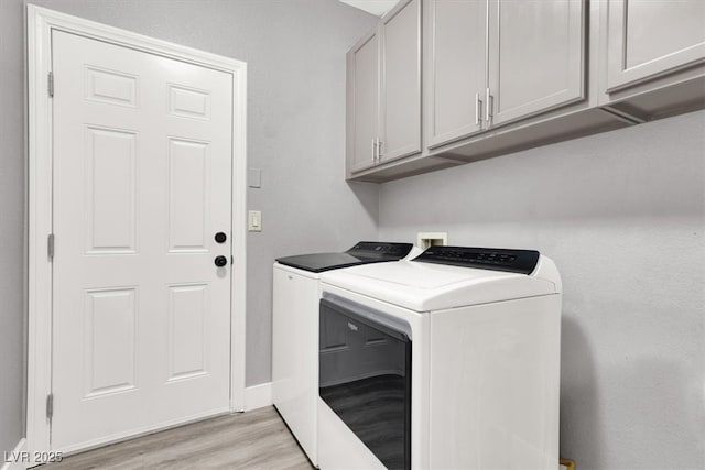 washroom with baseboards, cabinet space, light wood finished floors, and washing machine and clothes dryer