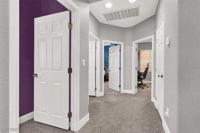 hall with carpet, visible vents, and baseboards