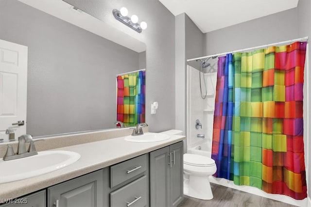 bathroom featuring double vanity, wood finished floors, a sink, and toilet