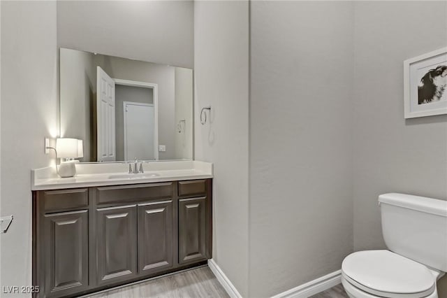 bathroom with baseboards, vanity, toilet, and wood finished floors