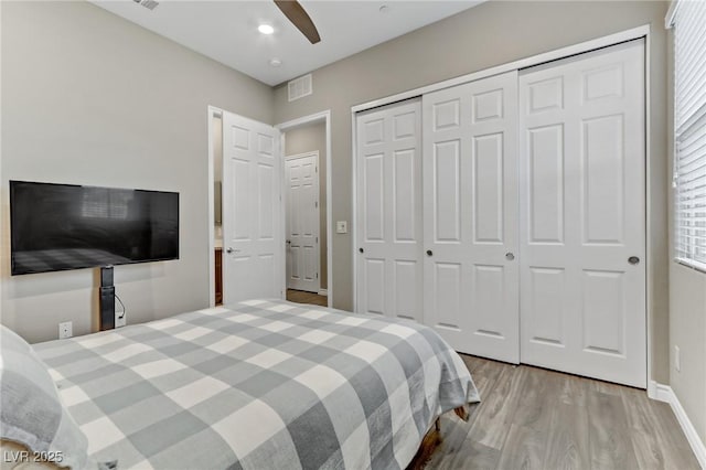 bedroom featuring wood finished floors, visible vents, baseboards, a ceiling fan, and a closet