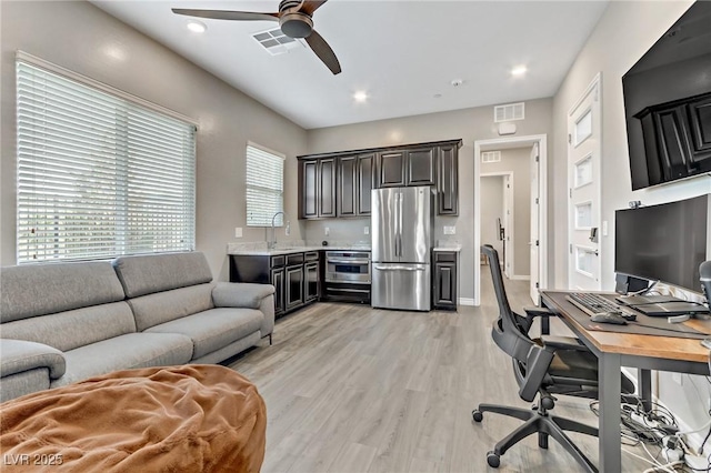 office space featuring light wood-style floors, visible vents, a sink, and a ceiling fan