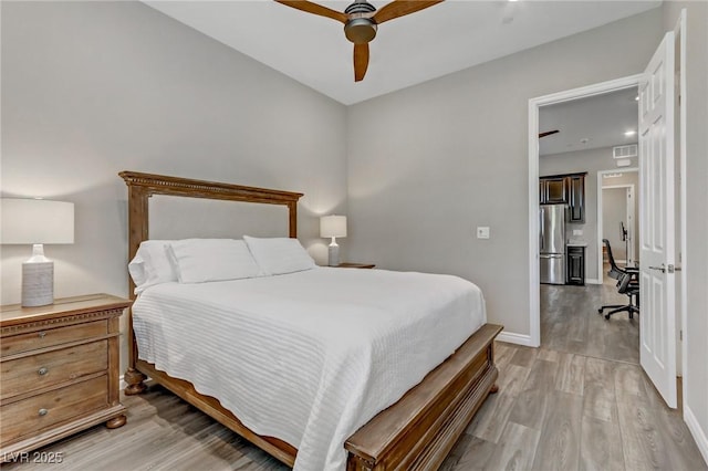 bedroom featuring visible vents, baseboards, ceiling fan, freestanding refrigerator, and light wood-style floors