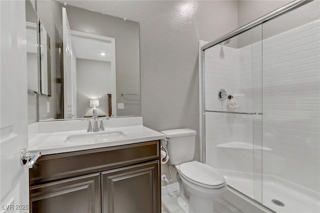 bathroom with toilet, a stall shower, and vanity