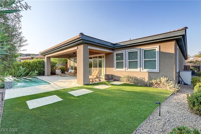 back of property with a fenced in pool, fence, a yard, a patio area, and stucco siding