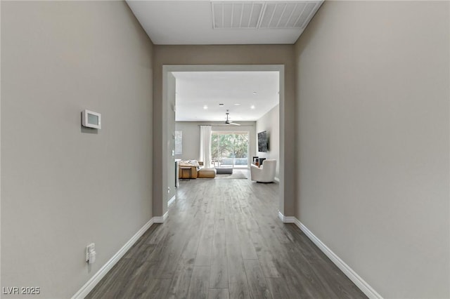 corridor with dark wood finished floors, visible vents, and baseboards