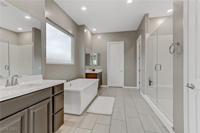 bathroom with a stall shower, a soaking tub, a sink, and recessed lighting