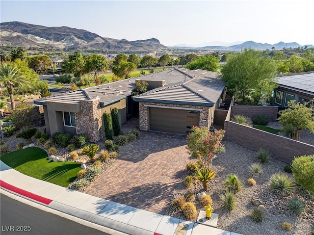 view of front of property with decorative driveway, an attached garage, a mountain view, fence, and stone siding