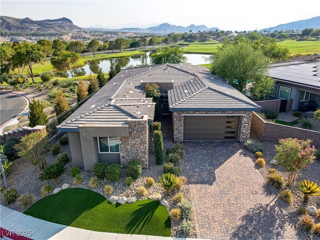 view of front facade with decorative driveway, stucco siding, a water and mountain view, a garage, and a tiled roof