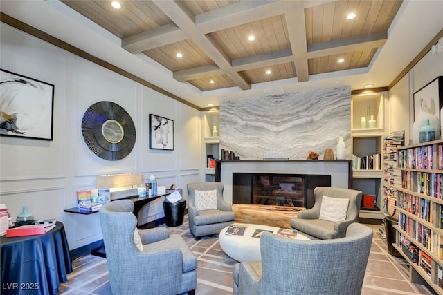 interior space featuring a glass covered fireplace, coffered ceiling, a decorative wall, and beamed ceiling