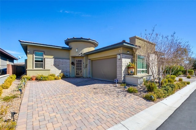 view of front of home with decorative driveway, an attached garage, fence, and stucco siding