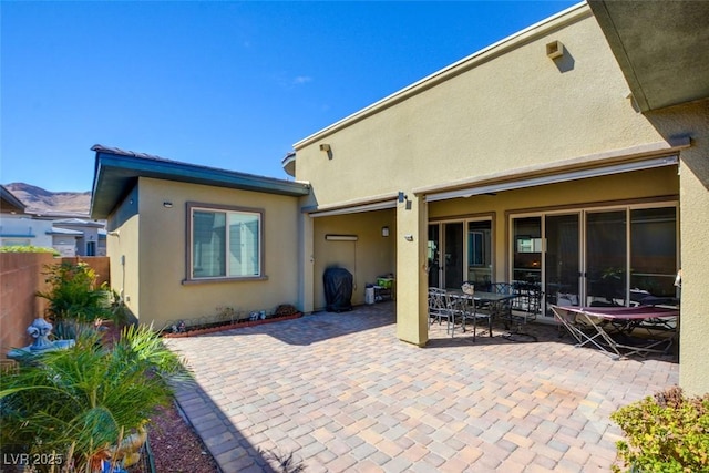 rear view of property featuring a patio, fence, and stucco siding