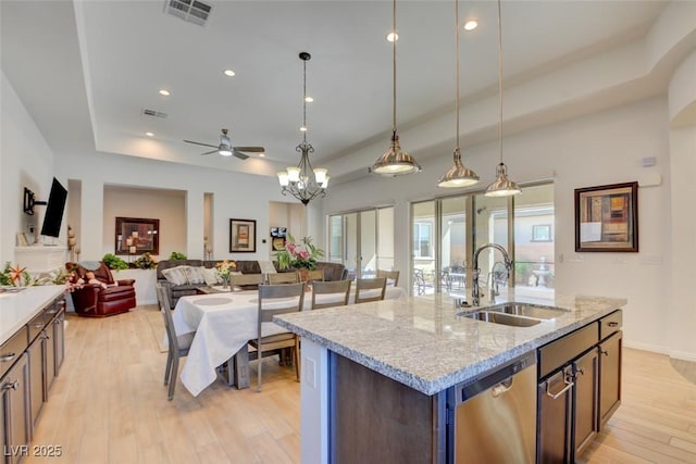 kitchen featuring visible vents, dishwasher, light wood-style flooring, a tray ceiling, and a sink