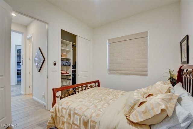 bedroom featuring a closet, wood finished floors, and baseboards