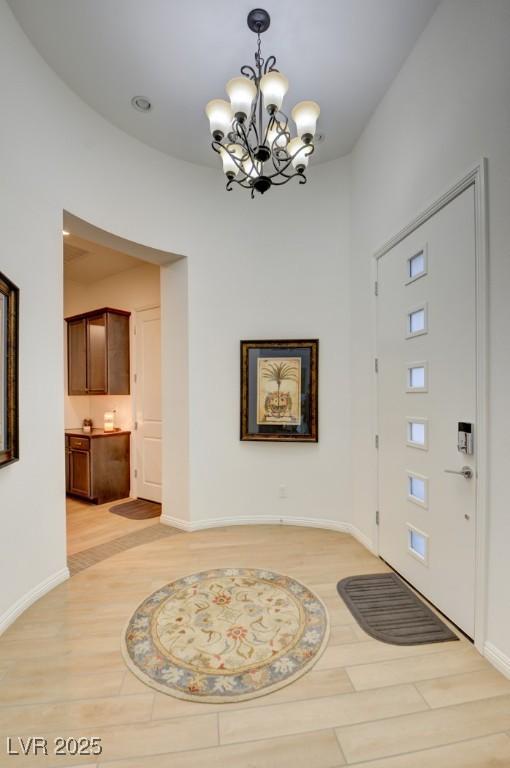 foyer with light wood-style floors, baseboards, and an inviting chandelier