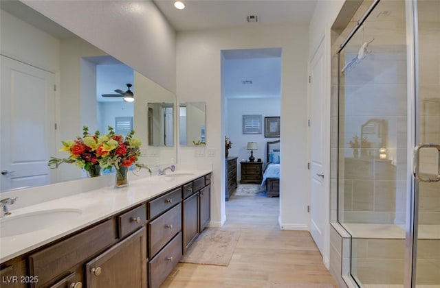 ensuite bathroom featuring a sink, a shower stall, and wood finished floors