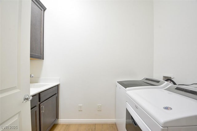 washroom featuring cabinet space, baseboards, light wood-style floors, and independent washer and dryer