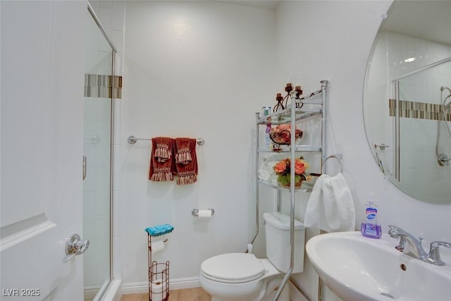 full bath featuring toilet, a shower stall, baseboards, and a sink