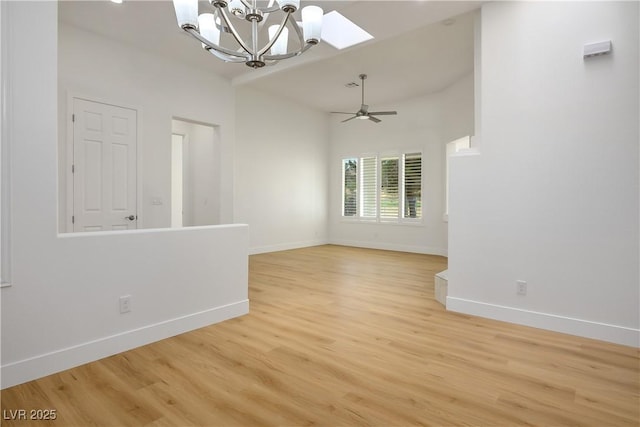 empty room with ceiling fan with notable chandelier, light wood-style flooring, and baseboards