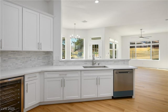 kitchen with backsplash, stainless steel dishwasher, white cabinets, a sink, and beverage cooler