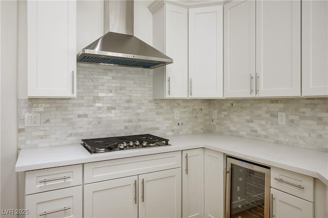 kitchen with wine cooler, stainless steel gas cooktop, tasteful backsplash, light countertops, and wall chimney exhaust hood