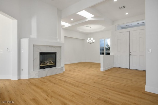 unfurnished living room with light wood-style floors, visible vents, a chandelier, and a tiled fireplace