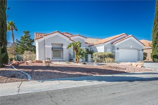 mediterranean / spanish-style home featuring concrete driveway, a tiled roof, an attached garage, and stucco siding