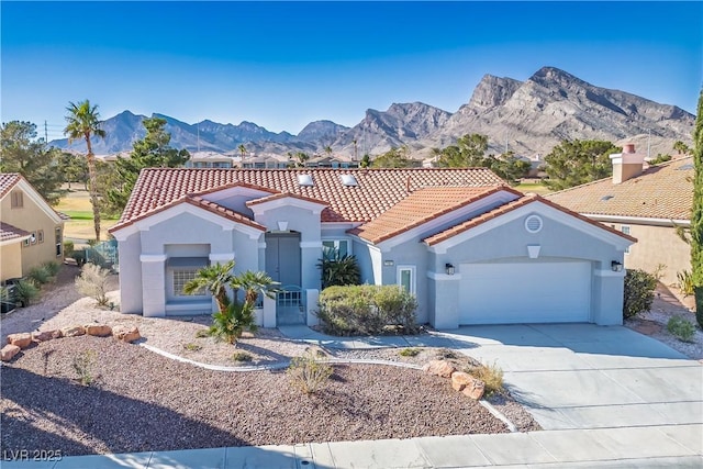 mediterranean / spanish-style home with stucco siding, an attached garage, a mountain view, driveway, and a tiled roof