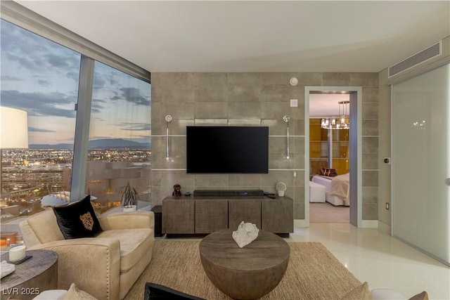 living room featuring a chandelier and tile walls