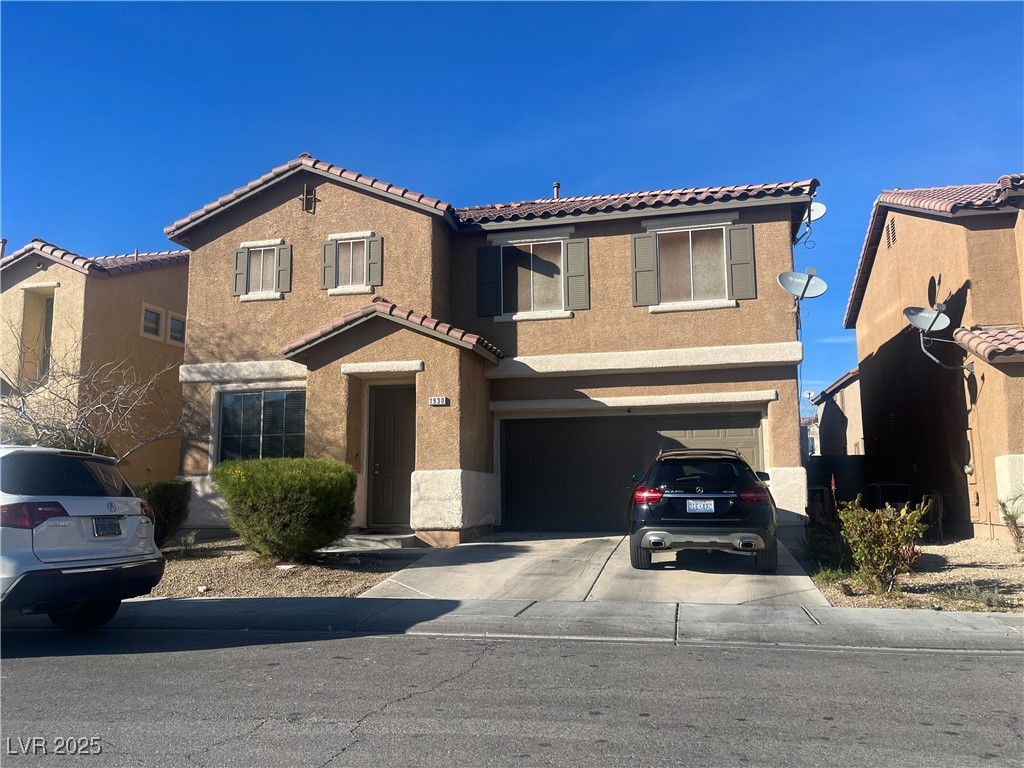 view of front of property featuring driveway, a tile roof, a garage, and stucco siding