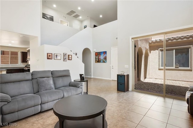 living room with light tile patterned floors, arched walkways, a towering ceiling, and recessed lighting