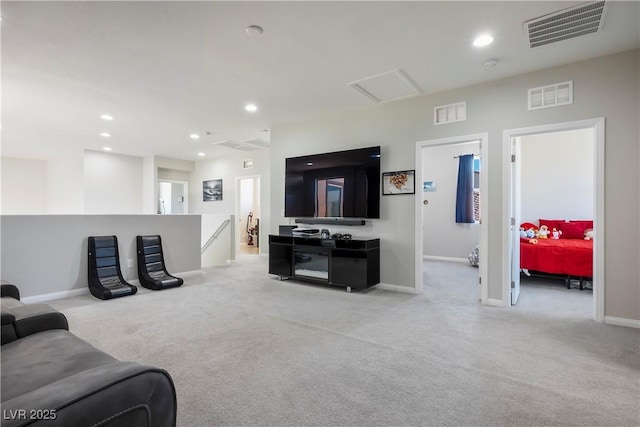 living area featuring attic access, visible vents, light colored carpet, and recessed lighting