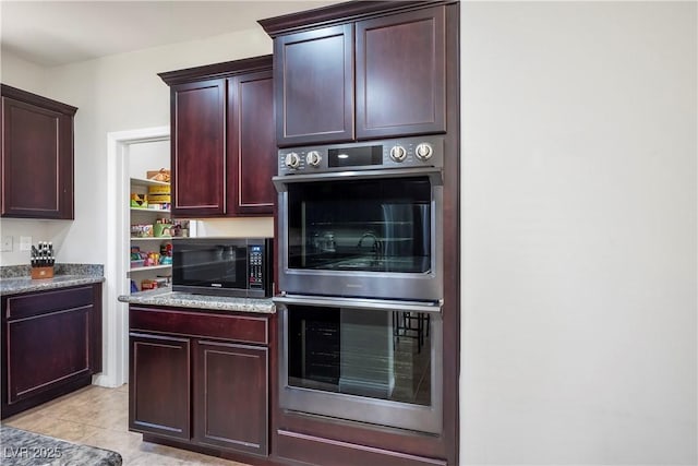 kitchen with double oven, stone counters, and light tile patterned floors