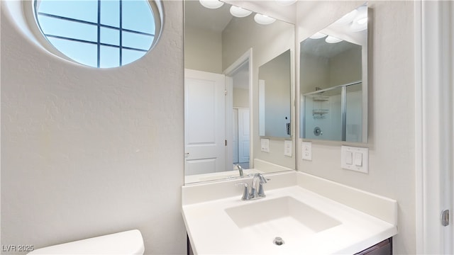 bathroom with an enclosed shower, vanity, and toilet