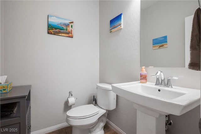 bathroom featuring a sink, toilet, and baseboards