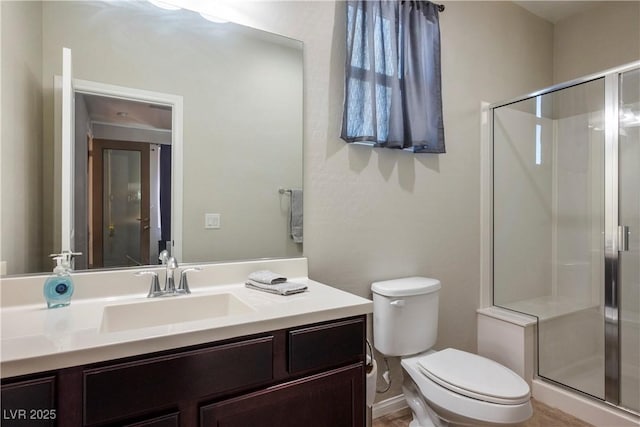 bathroom featuring toilet, a shower stall, and vanity