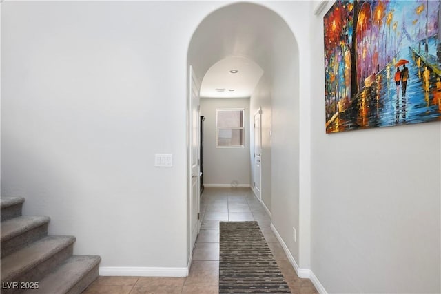 hallway with light tile patterned floors, stairway, and baseboards